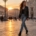 Donna con giacca di pelle nera da motociclista in piazza al tramonto